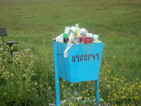 Ящик для мусора фактически установлен в поле. Позади место для отдыха - стол и стулья...